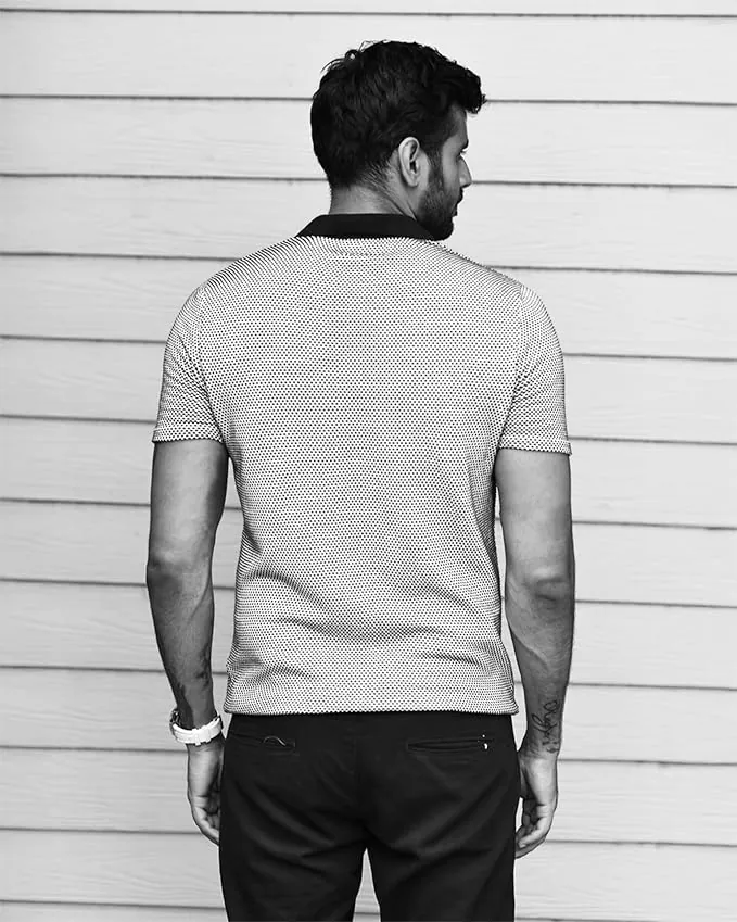Front view of the Posh Monk flat-knit polo laid on a wooden table in soft daylight