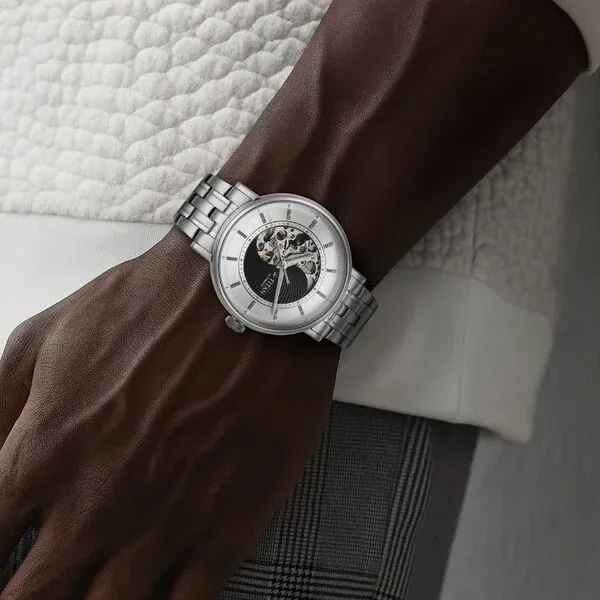 Lifestyle image of a man in a tailored navy blazer rolling up his shirt cuff to reveal the silver Titan watch during a coffee meeting