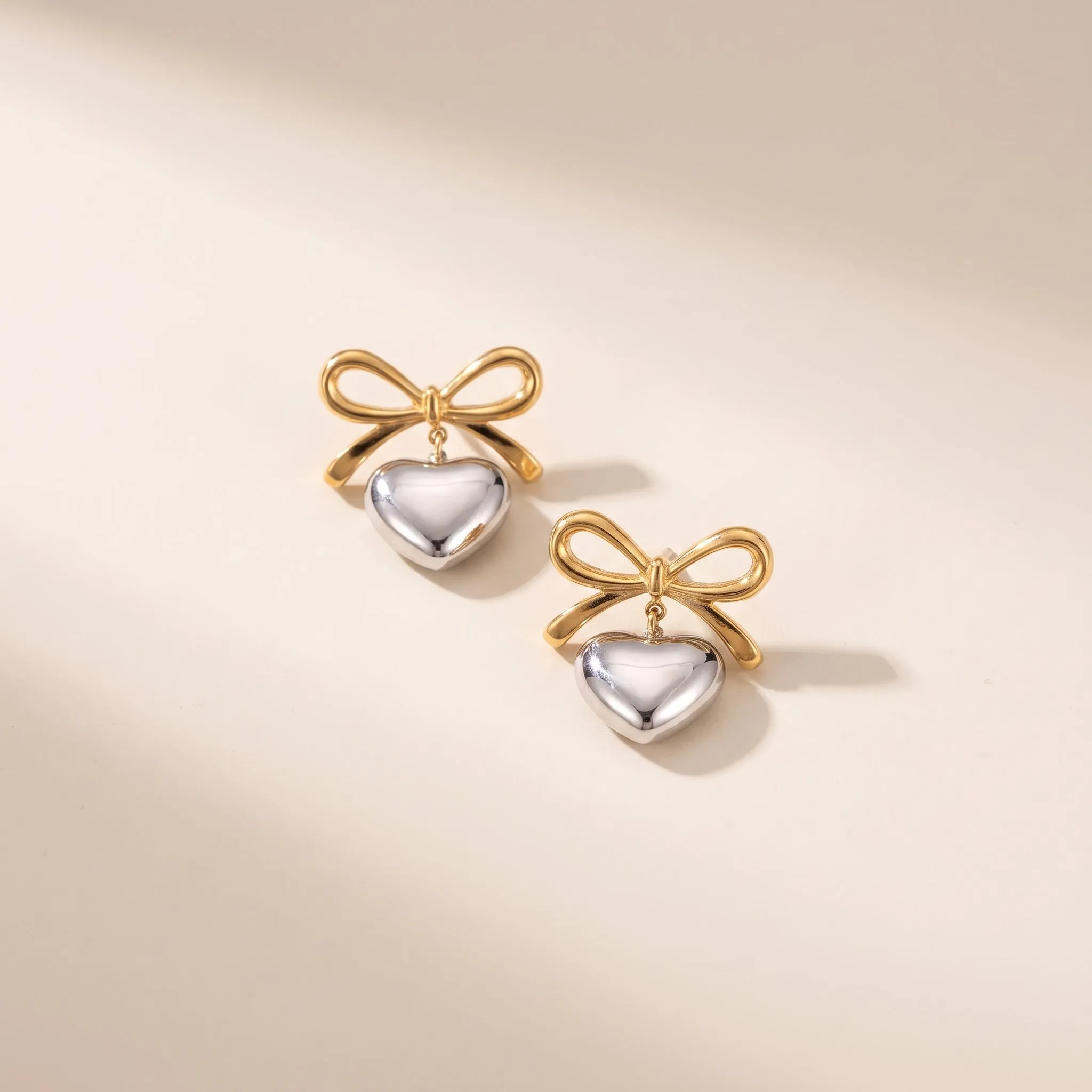Love Heart Earrings displayed on cream fabric with soft golden lighting