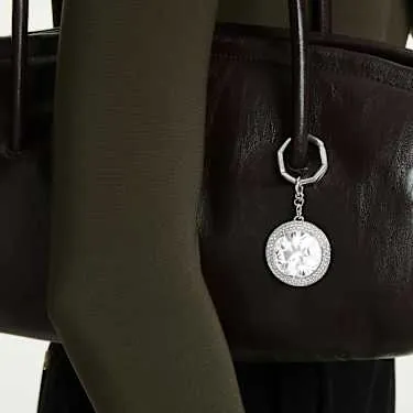Macro shot of the pavé crystal surround encircling the central round-cut stone on the white Swarovski bag charm